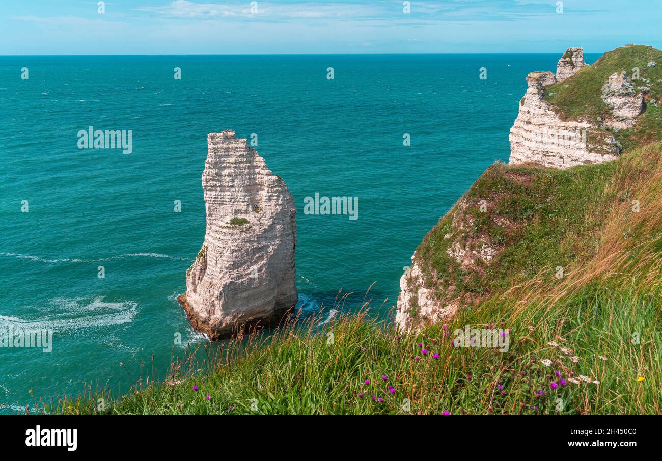 Etretat è meglio conosciuta per le sue scogliere di gesso, tra cui tre archi naturali e una formazione appuntita chiamata Aiguille o l'ago Foto Stock
