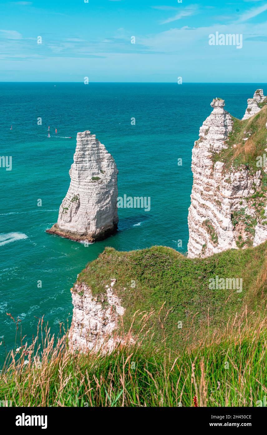 Etretat è meglio conosciuta per le sue scogliere di gesso, tra cui tre archi naturali e una formazione appuntita chiamata Aiguille o l'ago Foto Stock