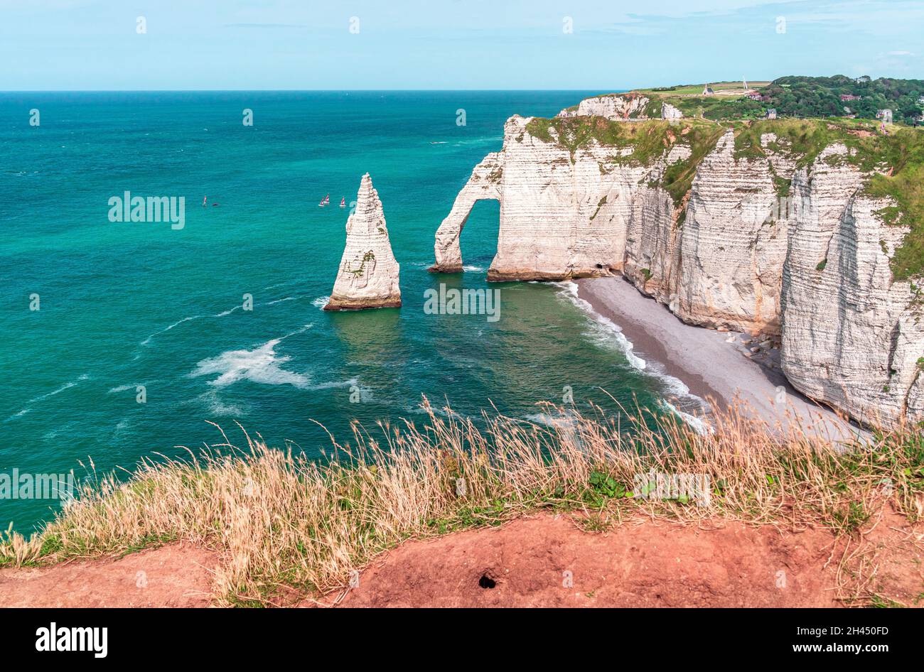 Etretat è meglio conosciuta per le sue scogliere di gesso, tra cui tre archi naturali e una formazione appuntita chiamata Aiguille o l'ago Foto Stock
