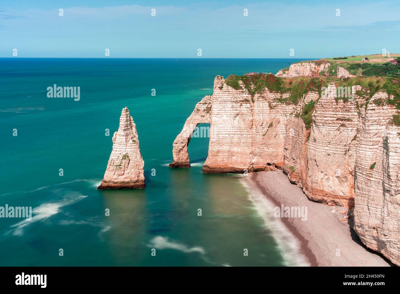 Etretat è meglio conosciuta per le sue scogliere di gesso, tra cui tre archi naturali e una formazione appuntita chiamata Aiguille o l'ago Foto Stock