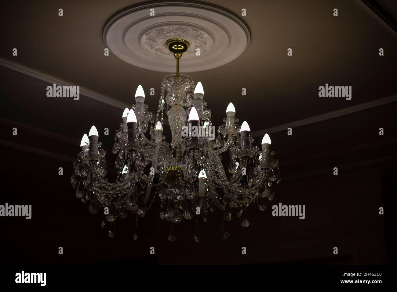 Lampadario in vetro. Sorgente luminosa da soffitto. Le lampade brillano attraverso un lampadario d'epoca. Foto Stock