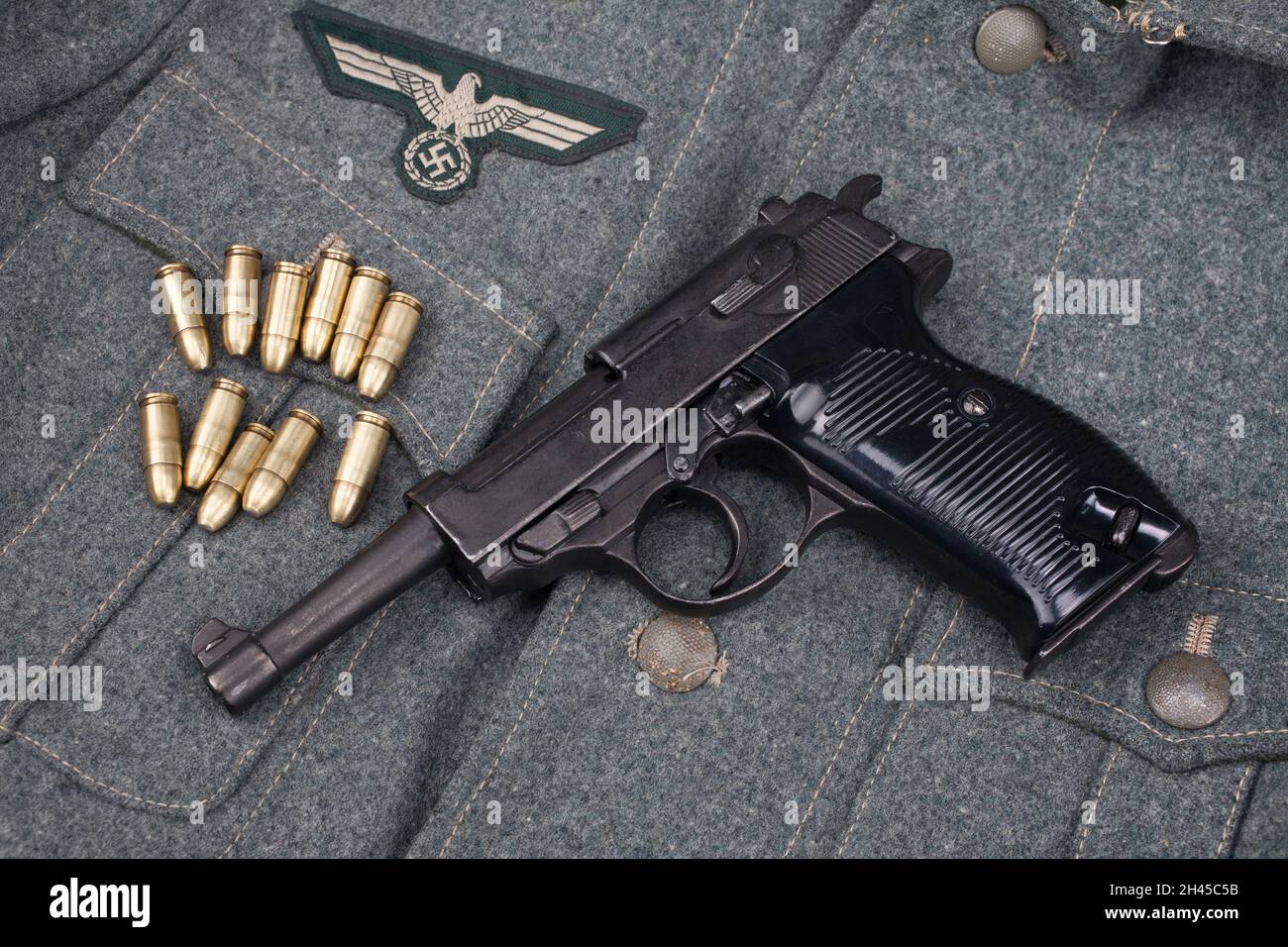 Guerra mondiale II esercito tedesco nazista pistola semiautomatica da 9 mm con munizioni su sfondo uniforme grigio dell'esercito Foto Stock