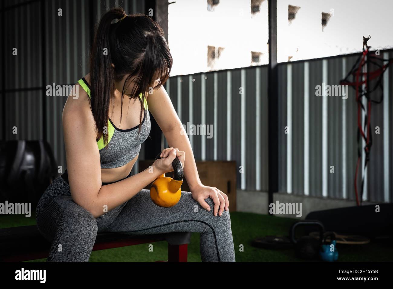 Le giovani donne asiatiche godono di esercitarsi con il campanello del bollitore di sollevamento con una mano alla palestra. concetto di bodybuilding di sport. Foto Stock