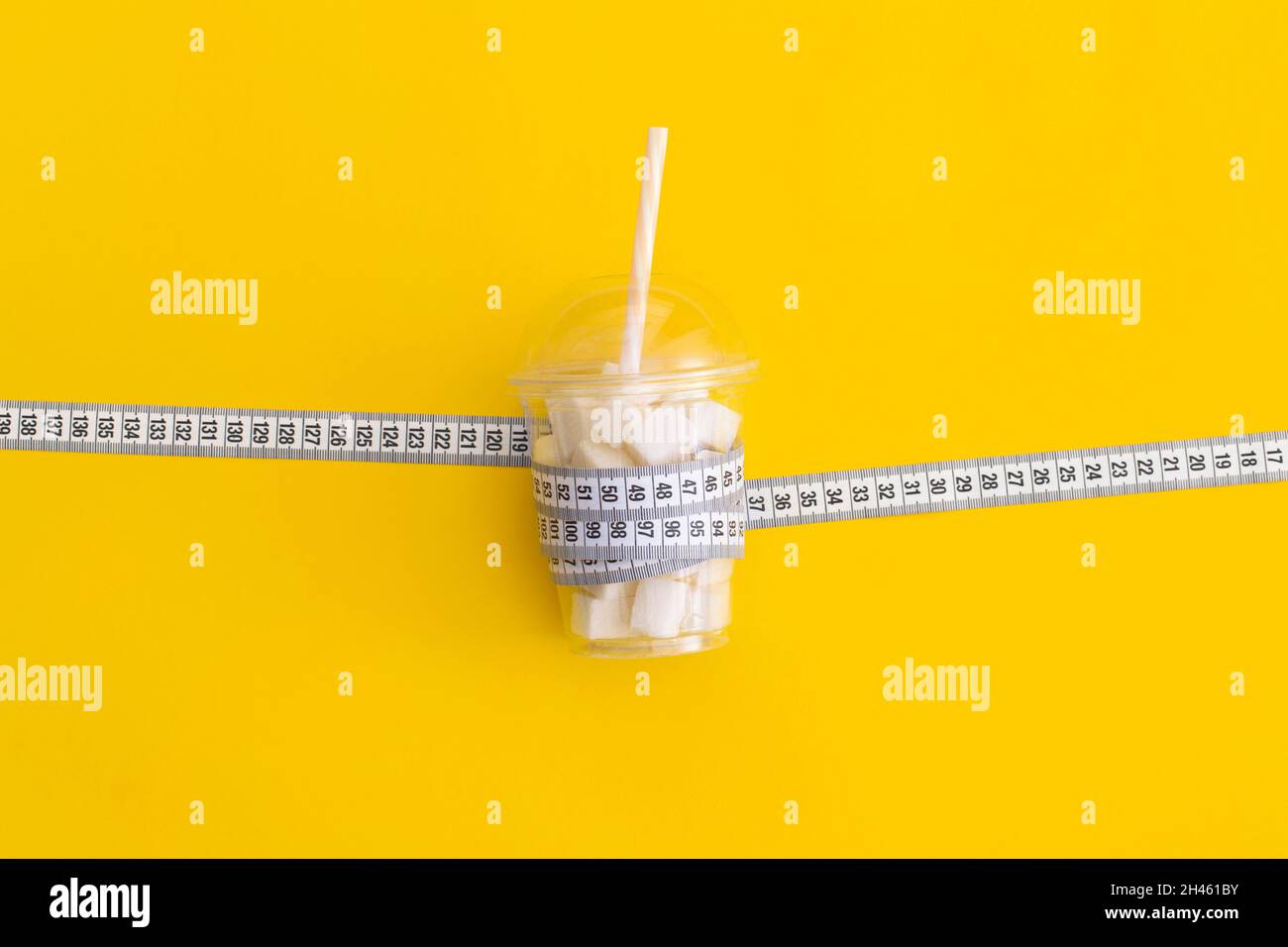 Nastro graduato e cubetti di zucchero su sfondo giallo. Diabete e perdita di peso concetto Foto Stock