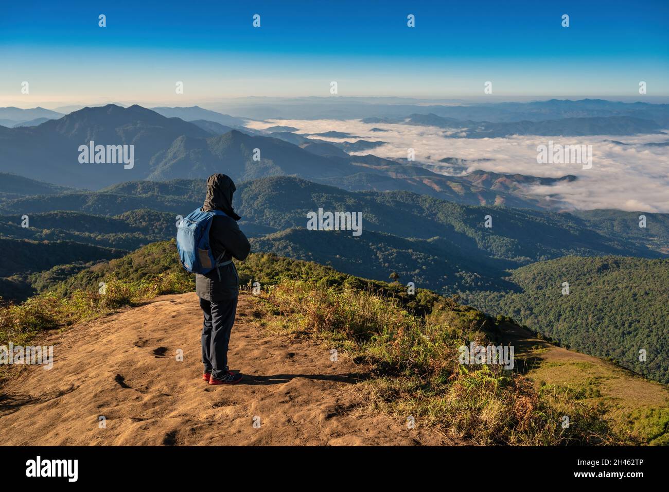 Uomo escursioni guardando la catena montuosa sulla cima della montagna nella foresta tropicale, Outdoor avventura concetto di viaggio Foto Stock