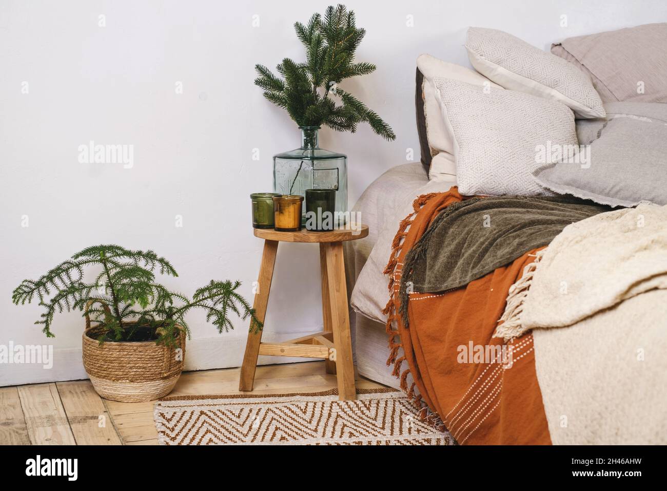 Livingroom decorazioni natalizie vicino a letto in stile ecologico, elementi naturali e vero abete in vaso e rami in vaso. Stile scandinavo, casa rustica Copia Foto Stock