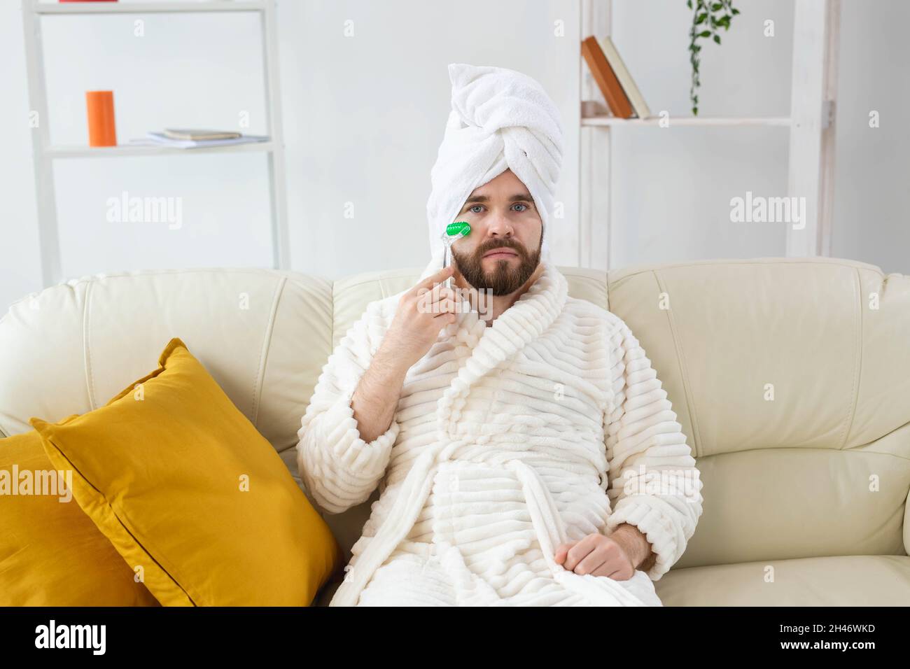 Uomo bearded con strumento di massaggio facciale. Cura della pelle maschile e concetto spa. Foto Stock