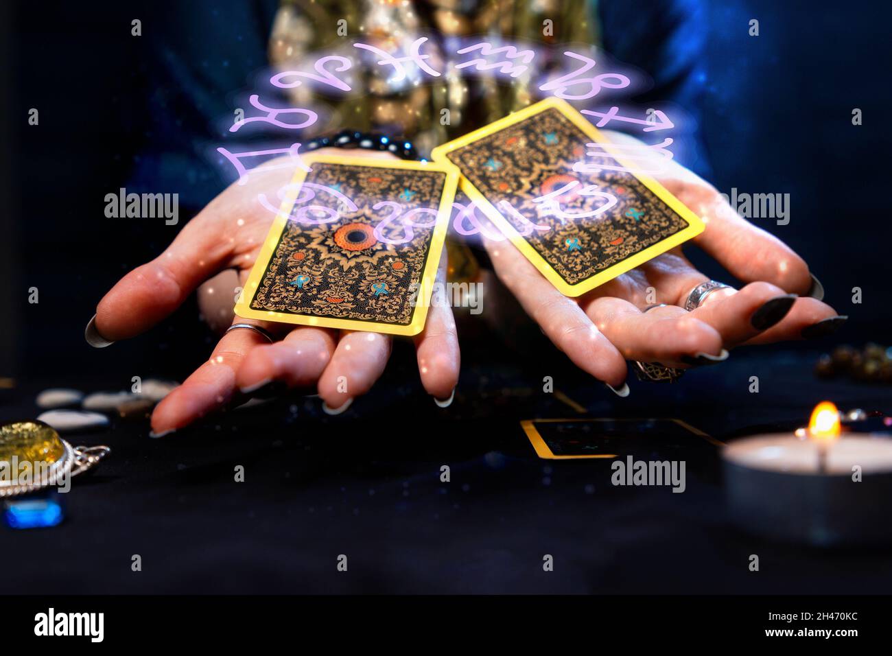 La cartomanza. Il cassiere della fortuna tiene fuori due carte Tarocchi sulle sue palme. Il cerchio zodiacale è raffigurato sopra la mano con le carte. Il concetto di div Foto Stock