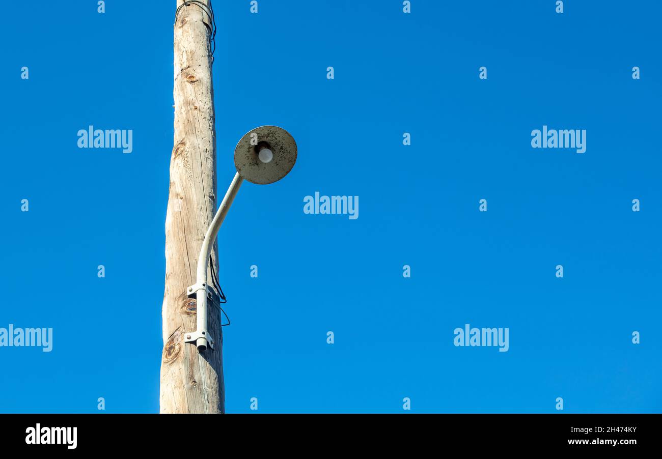 Streetlight retrò, lampadina appesa su palo elettrico in legno. Montante vintage con lampada. Cancella sfondo cielo blu vuoto, spazio di copia. Foto Stock