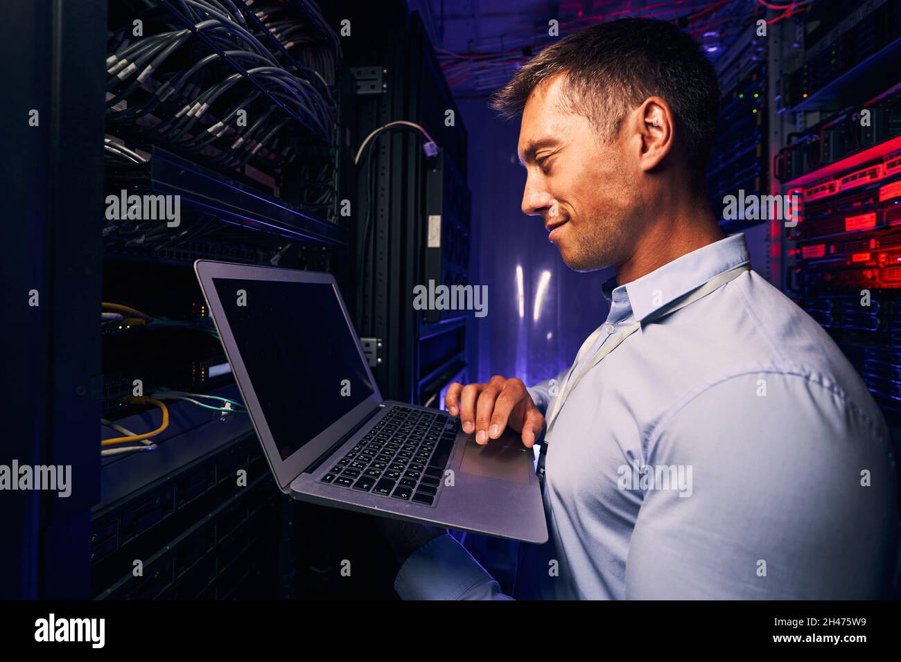 Sorridente soddisfatto amministratore di sistema che controlla le prestazioni del server Foto Stock