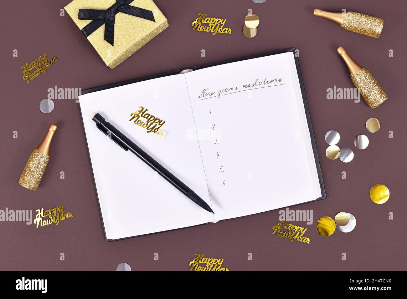 Le risoluzioni del nuovo anno. Scrivere una lista di piani in un notebook aperto circondato da decorazione festa di Capodanno Foto Stock