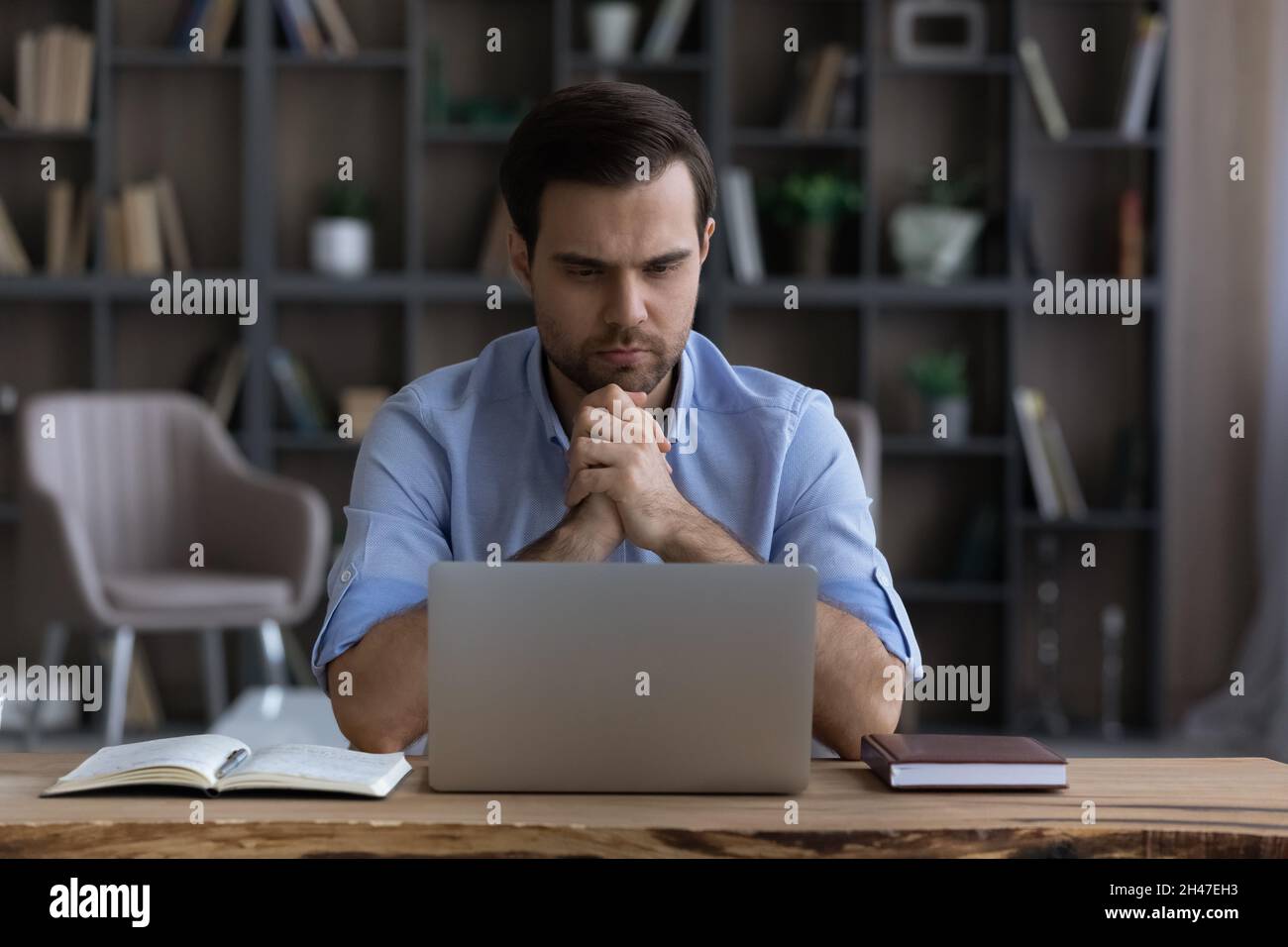 Pensivo giovane uomo d'affari che lavora al computer in ufficio domestico. Foto Stock