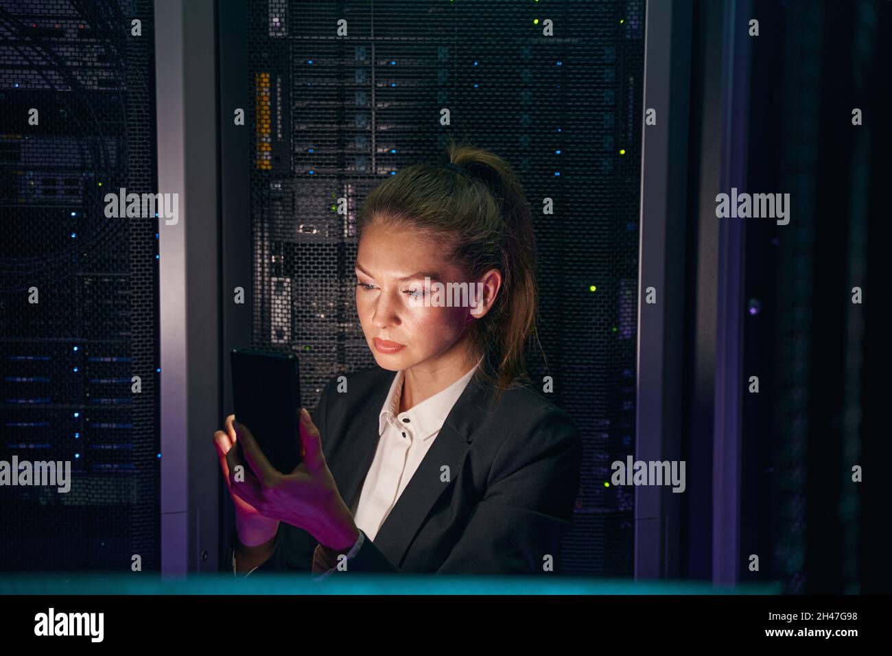 L'amministratore di sistema controlla i server con il cellulare nel data center Foto Stock