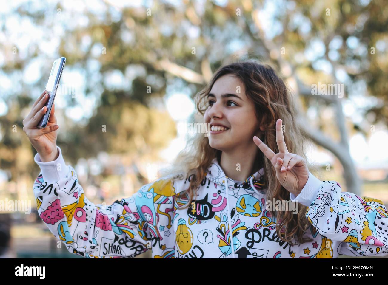 Ragazza sorridente graziosa che prende un selfie. Giovane ragazza all'aperto Foto Stock