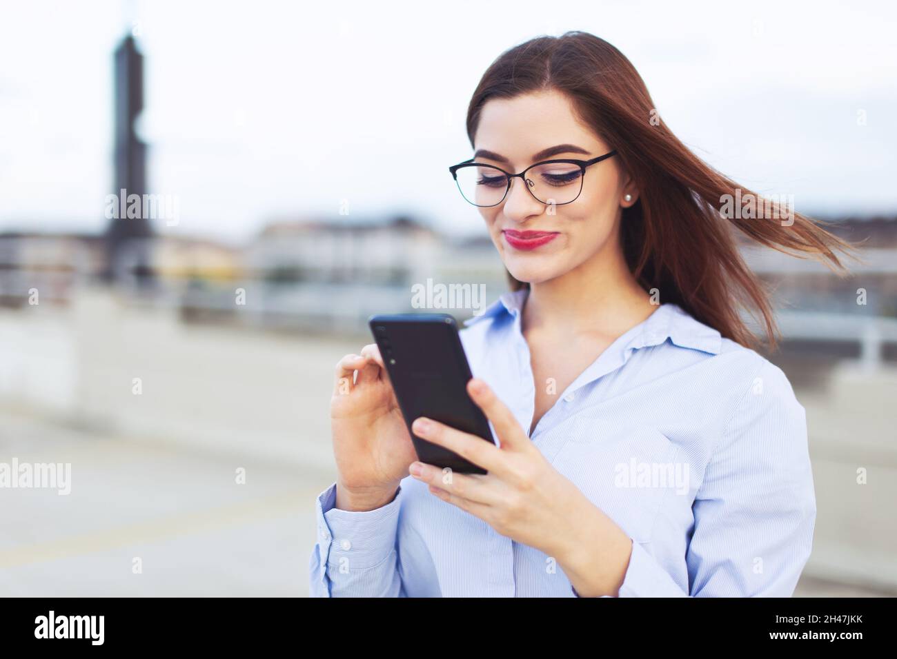 Giovane donna d'affari caucasica rossa con smartphone all'aperto Foto Stock