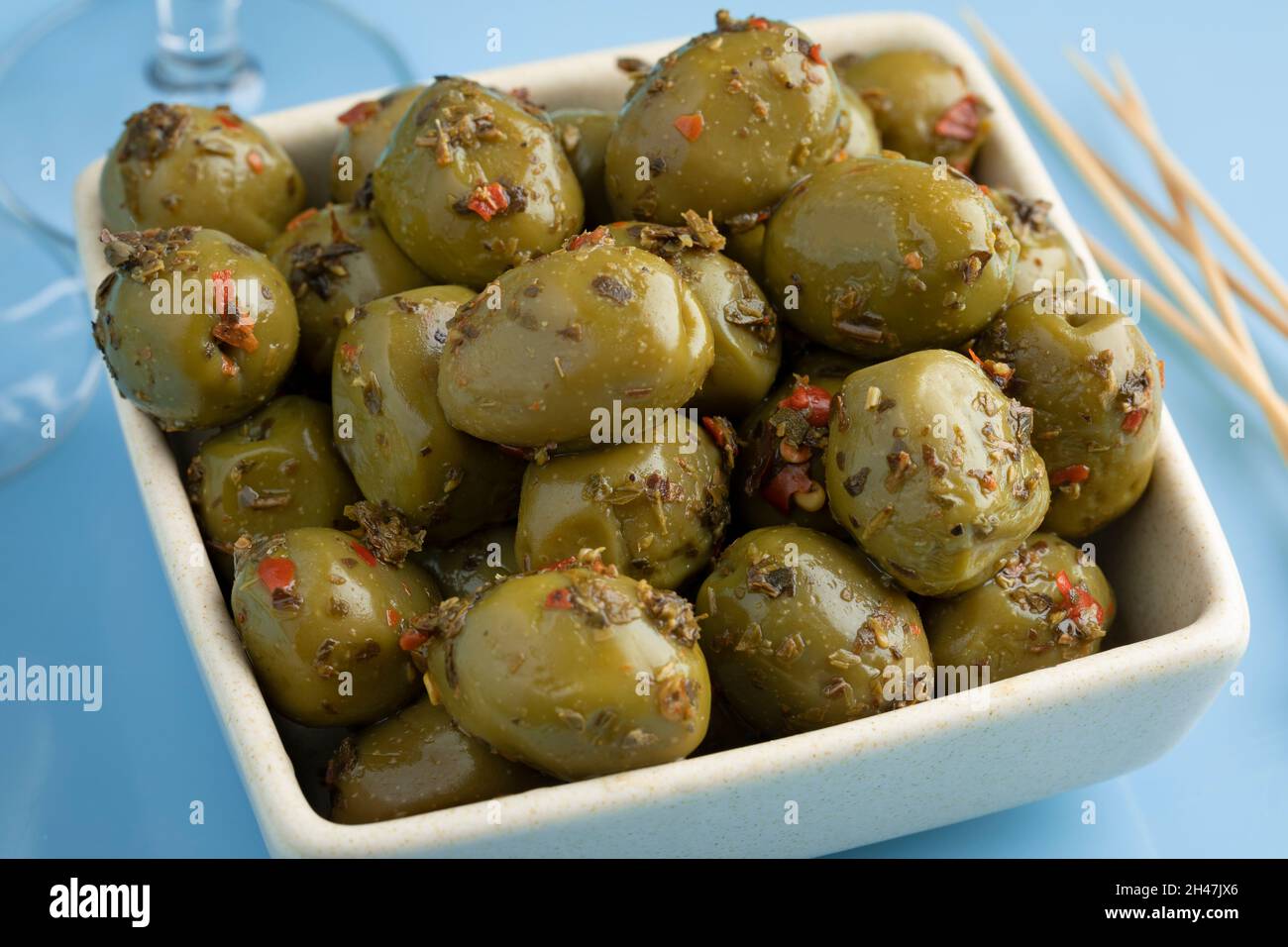 Ciotola con olive verdi greche e condimento da vicino Foto Stock