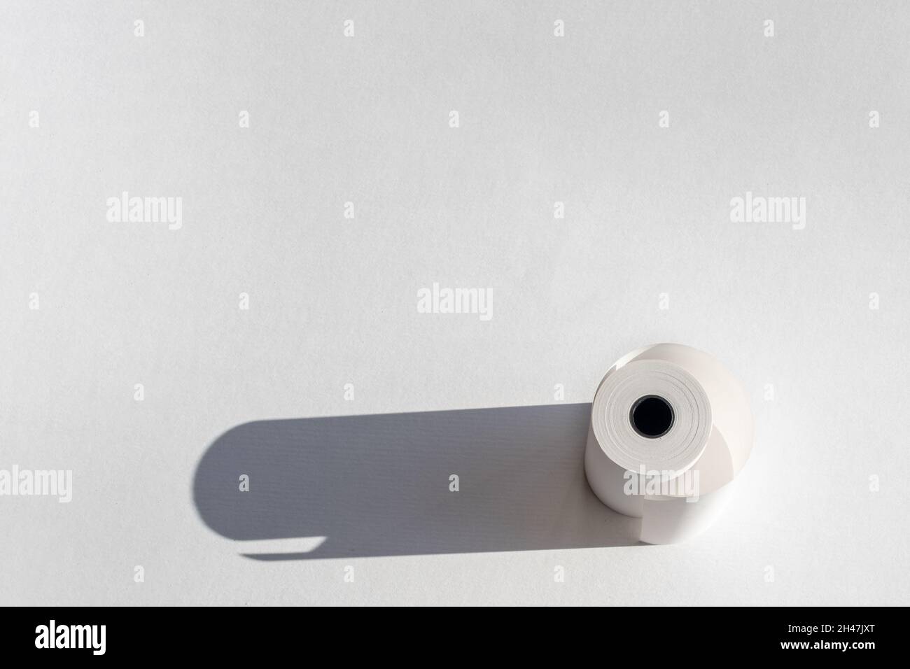 Rotolo di nastro di carta per cassette con ombreggiatura su carta bianca, spazio di copia. Rotolo di nastro per registratore di cassa, rotolo di carta per ricevute, isolato su sfondo bianco Foto Stock