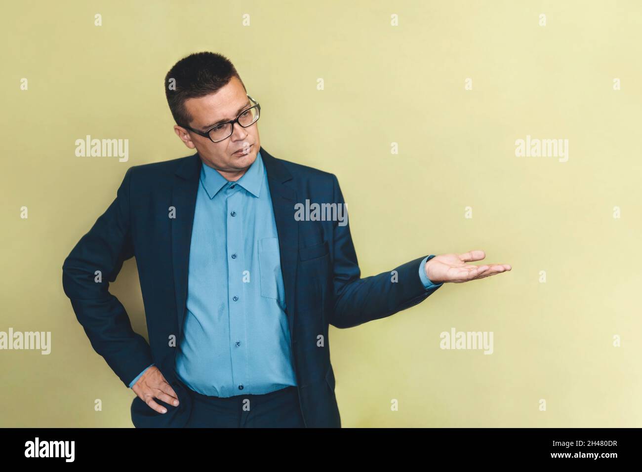 Uomo d'affari che tiene qualcosa senza tema. L'uomo in un abito blu punta al lato. Spazio di copia. Foto Stock