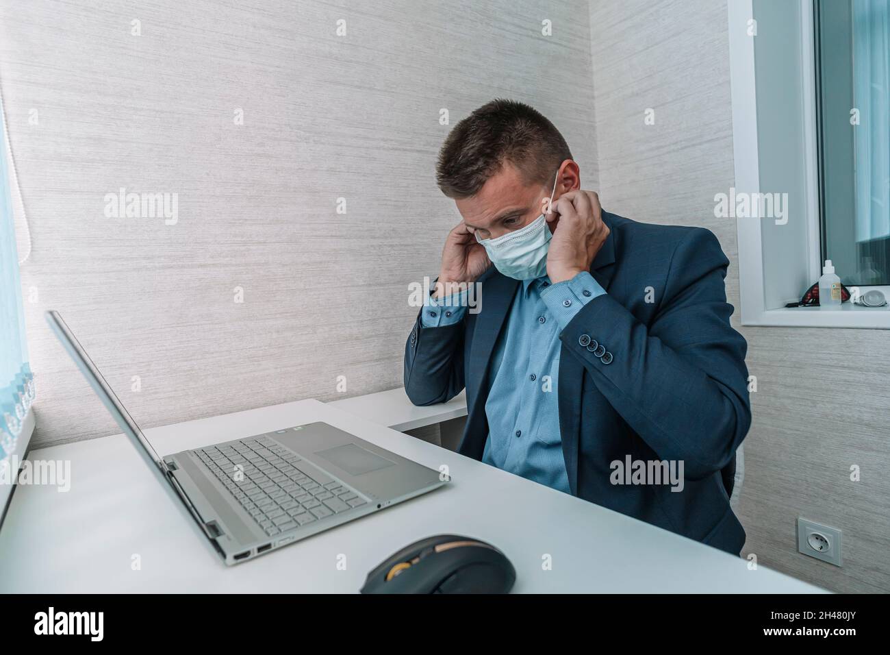 Minaccia virale, malattie virali stagionali. Un uomo lavora in ufficio in una maschera medica, proteggendo gli impiegati dai virus. Un uomo d'affari nelle offiche Foto Stock