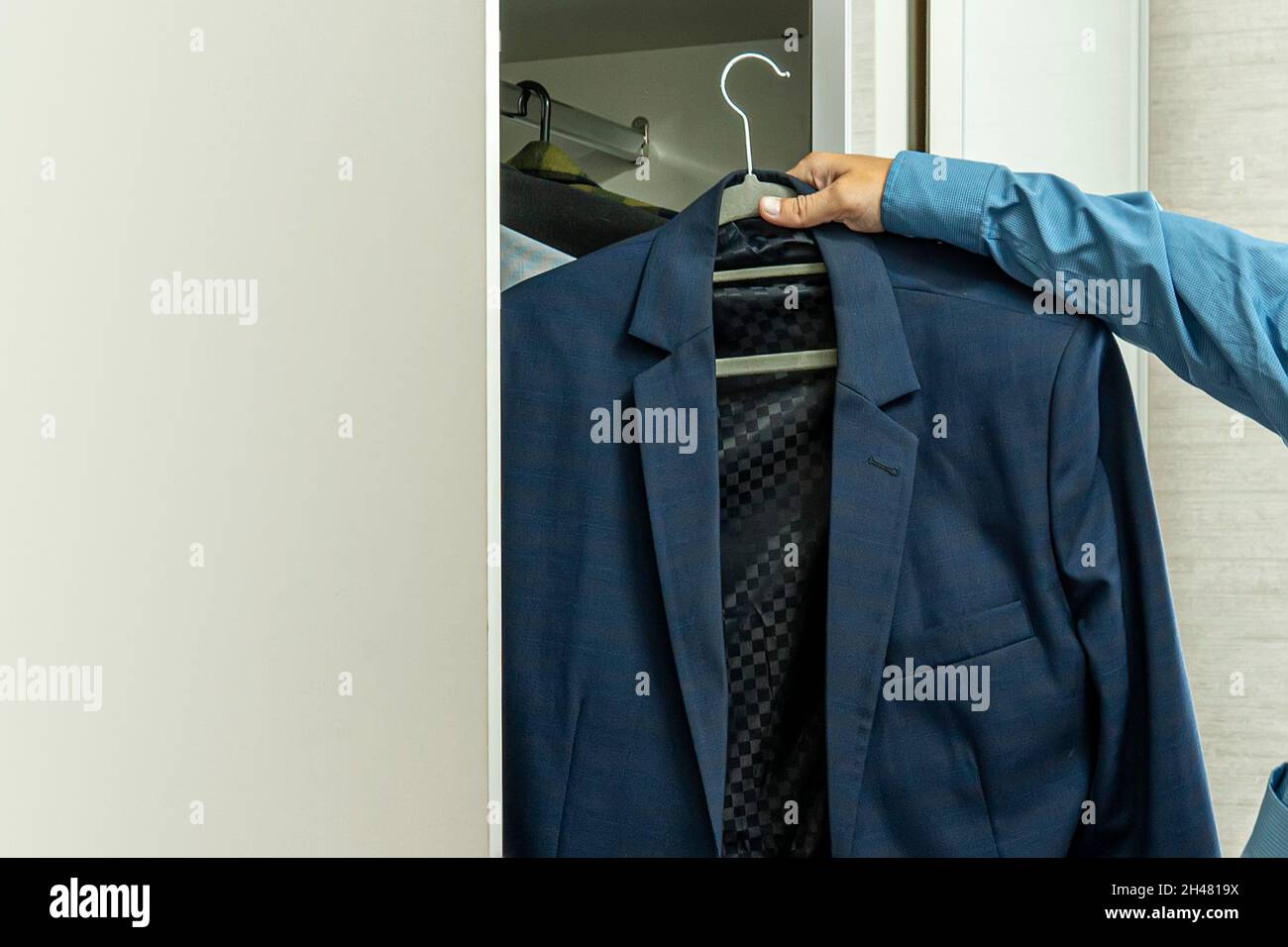 Uomo d'affari vestirsi per lavoro. Un giovane uomo d'affari maschile sceglie una giacca. È richiesto un abbigliamento da lavoro. Foto Stock