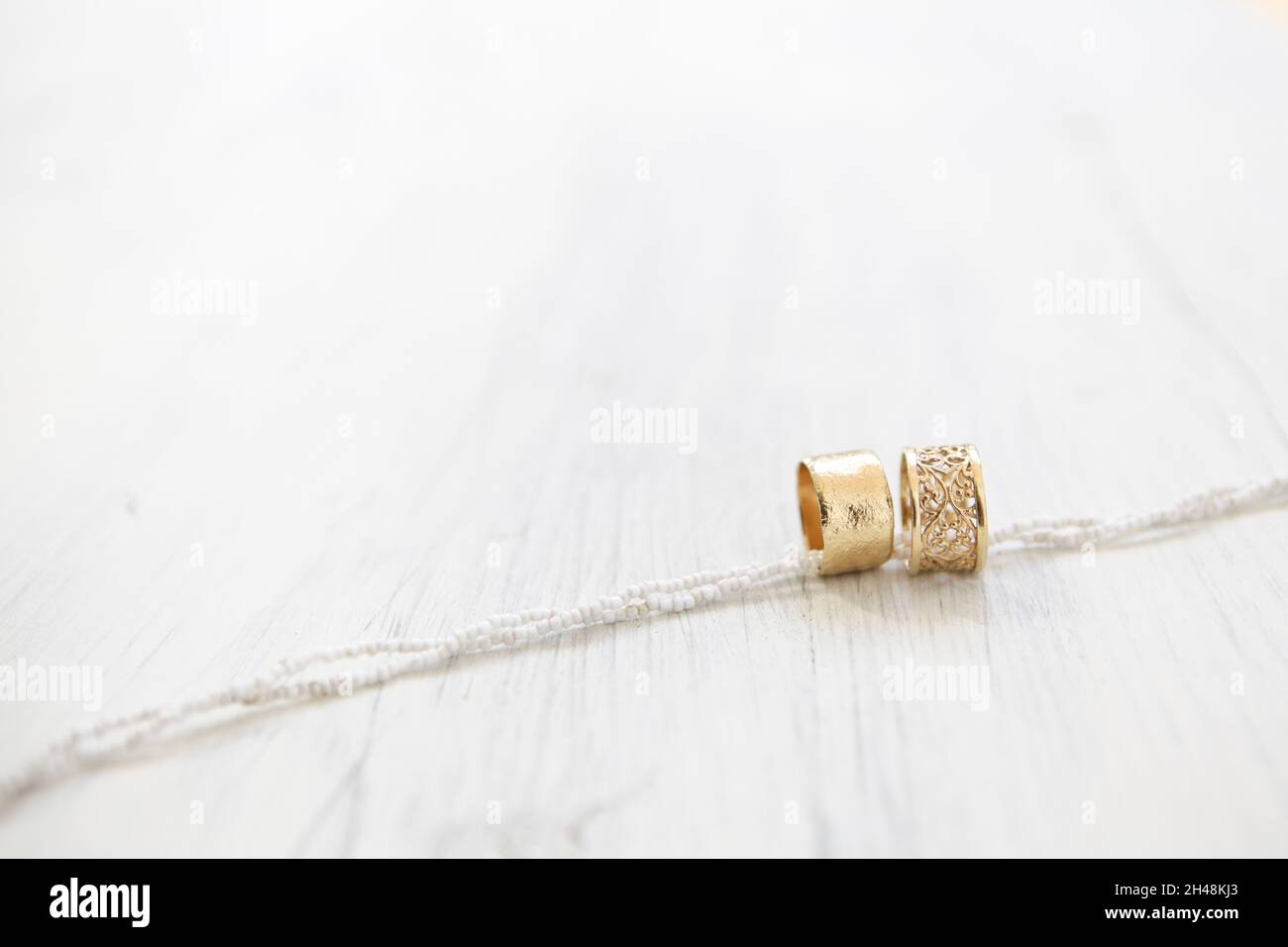 Anelli di nozze dorati su sfondo bianco di legno Foto Stock