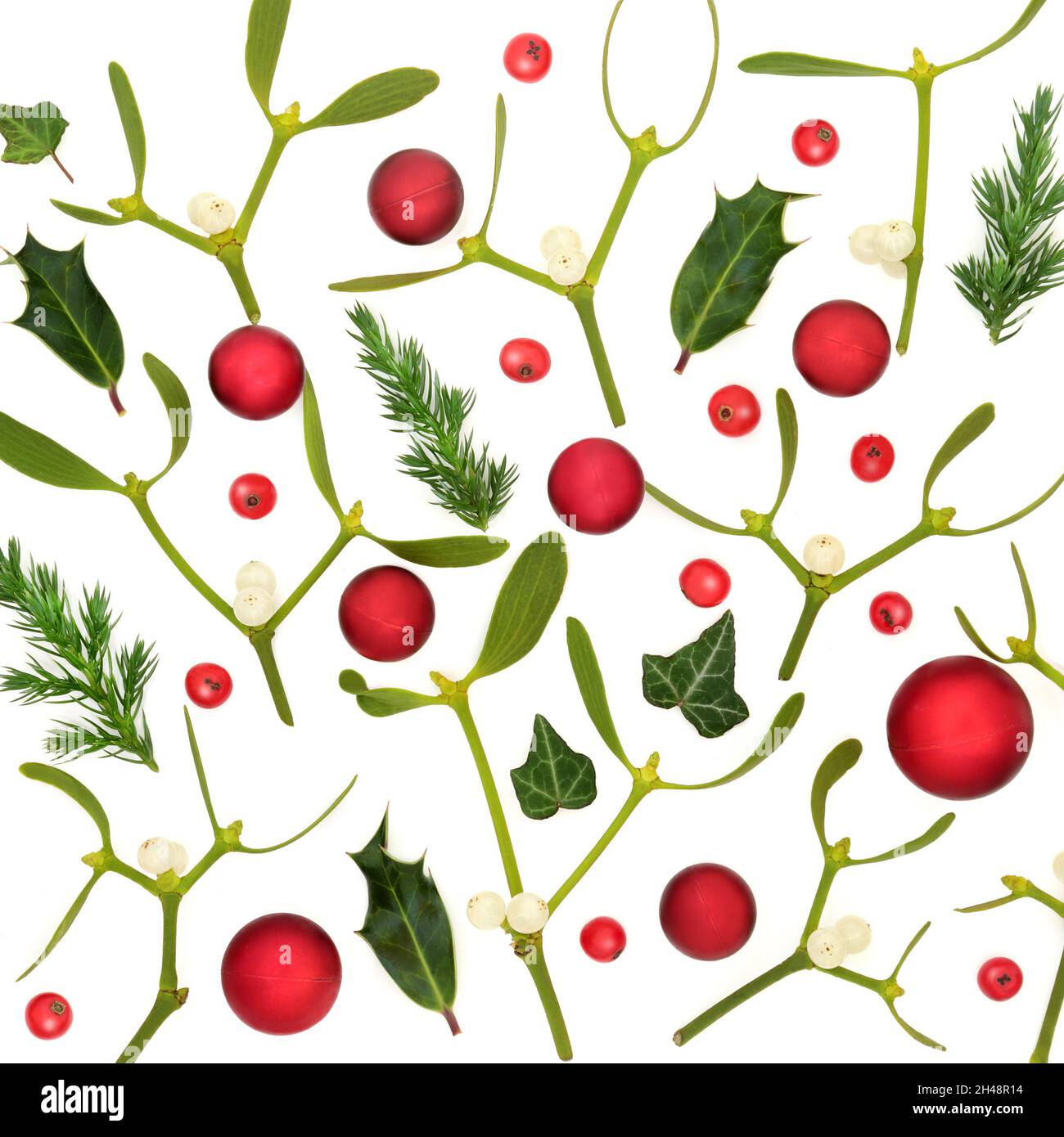 Composizione di Natale con palla rossa decorazioni boccale mistletoe, acini di agrifoglio e abete ginepro su bianco. Sfondo festivo per la stagione delle vacanze. Foto Stock