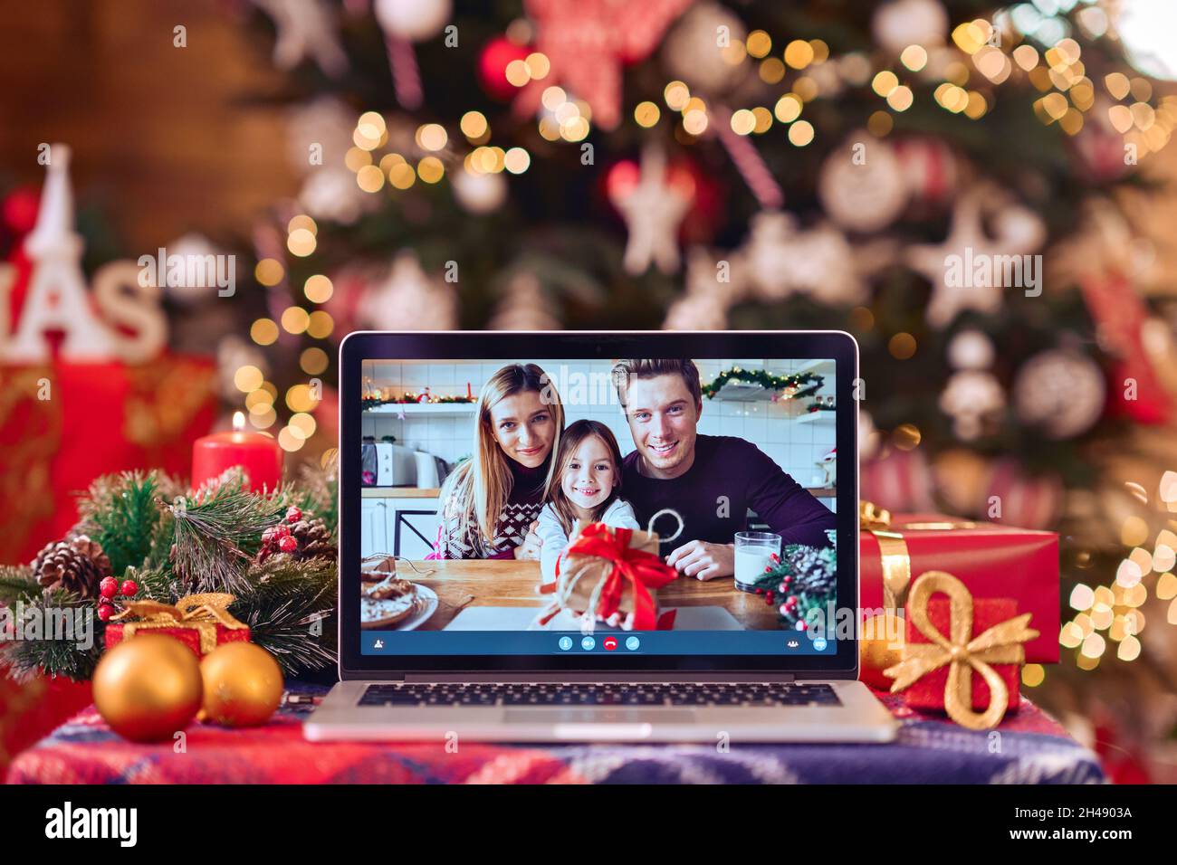 Videochiamata di famiglia sullo schermo del computer portatile sullo sfondo del tavolo di Natale. Foto Stock