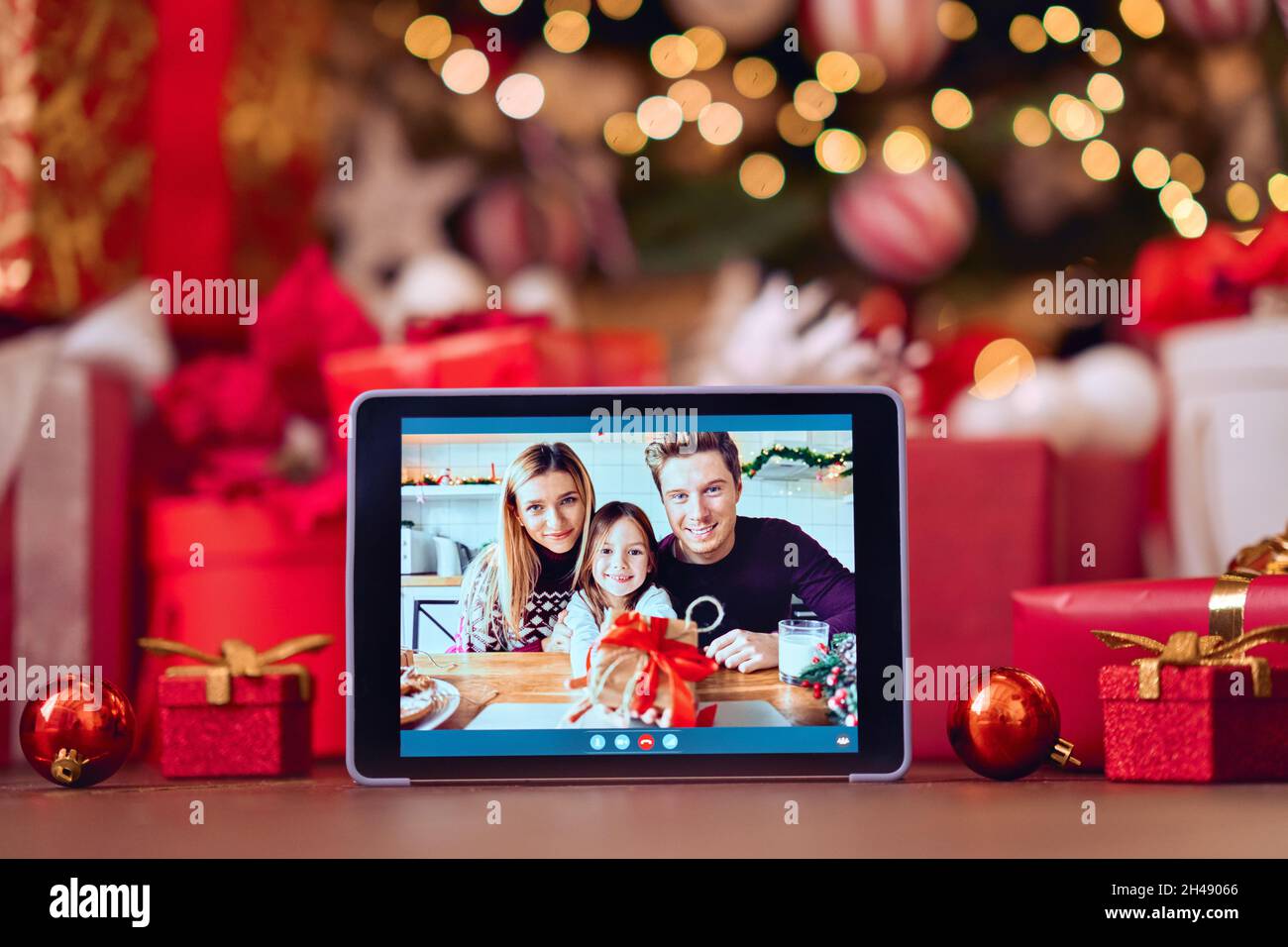 Videochiamata di famiglia sullo schermo del tablet digitale sullo sfondo del tavolo di Natale. Foto Stock