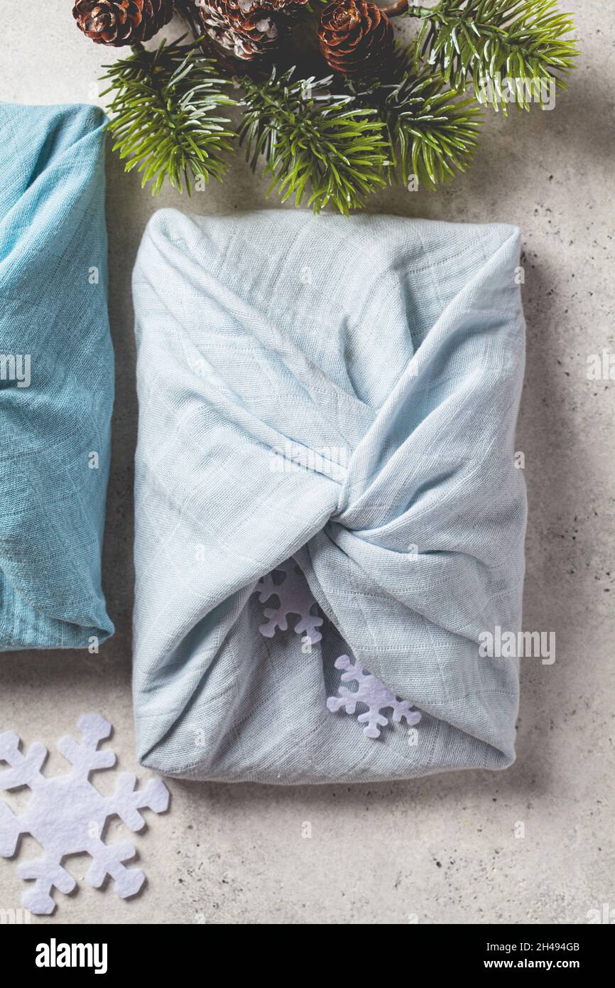 Articoli regalo in tessuto per Natale su sfondo grigio, vista dall'alto. Concetto di zero rifiuti. Stile Furoshiki. Foto Stock