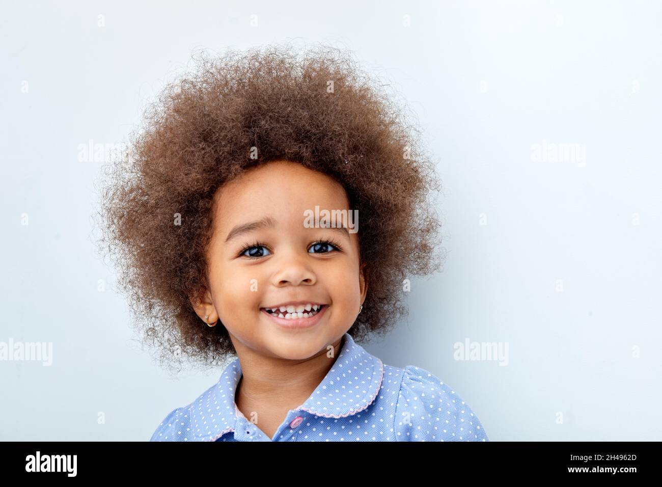 Primo piano ritratto della bambina africana ridendo, sorridendo, guardando la macchina fotografica. Bellissimo ragazzo nero con capelli ricci divertirsi, eccitato, avere buon moo Foto Stock