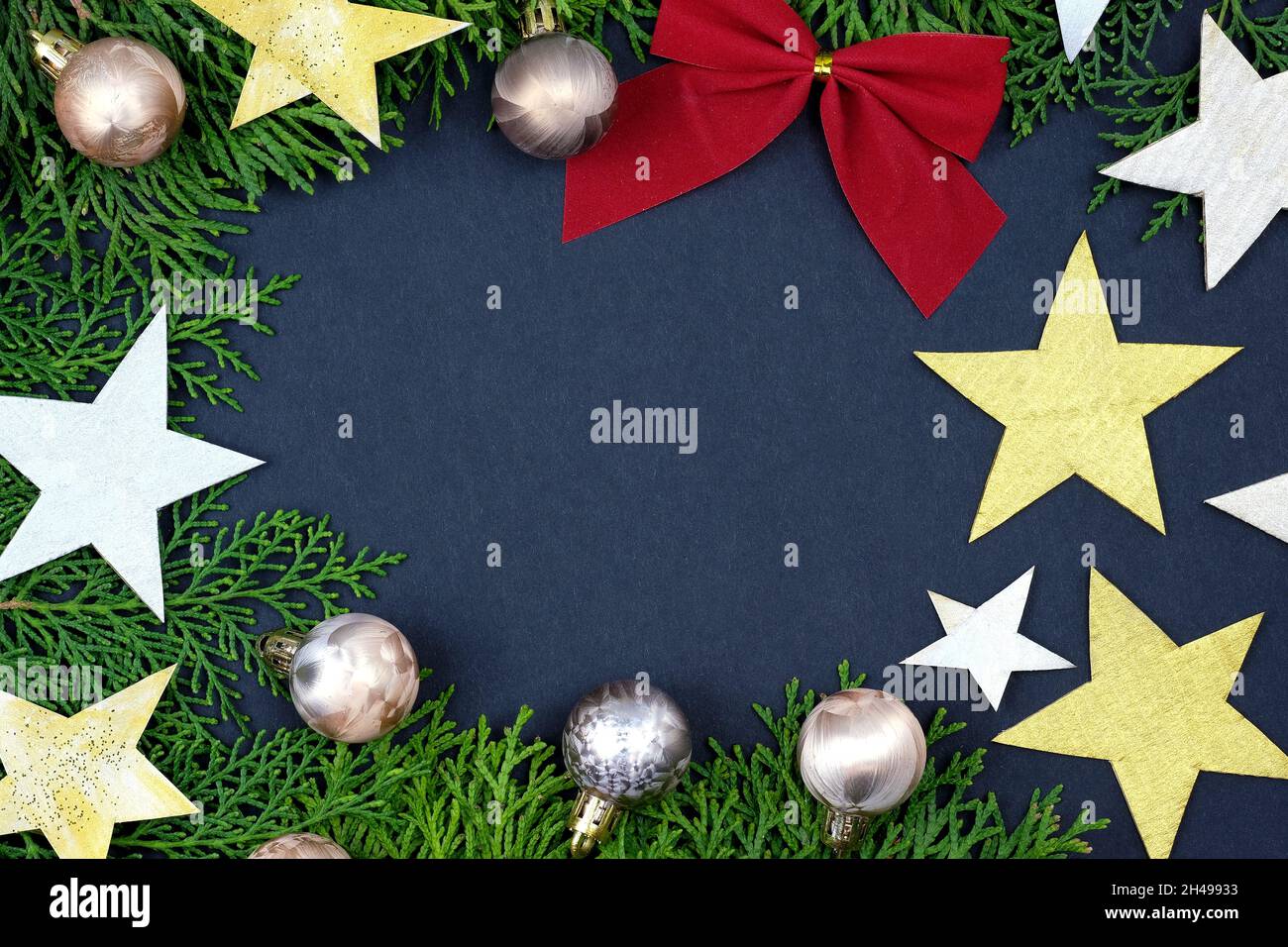 Cornice elegante per i saluti di Natale. Tema di Natale twigs thuja, stelle d'oro e palle per l'albero di Natale. Composizione del nuovo anno con bac nero Foto Stock