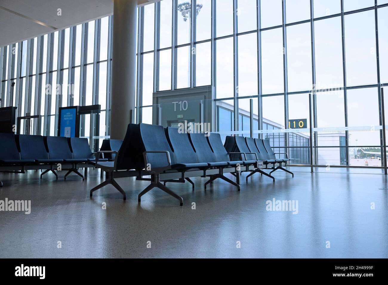 L'area d'attesa dell'aeroporto è vuota, con una grande finestra e nessuno, un posto pulito e spazioso Foto Stock