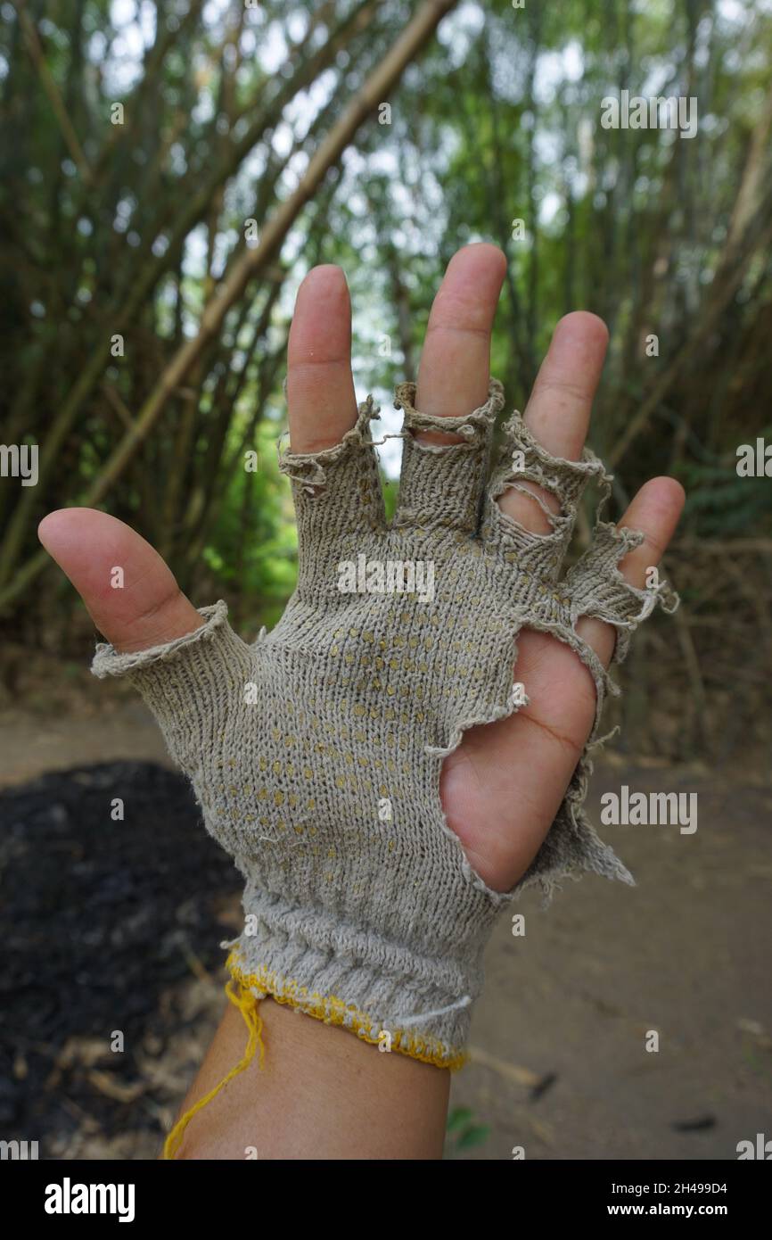 Mani con fori e guanti rotti Foto stock - Alamy