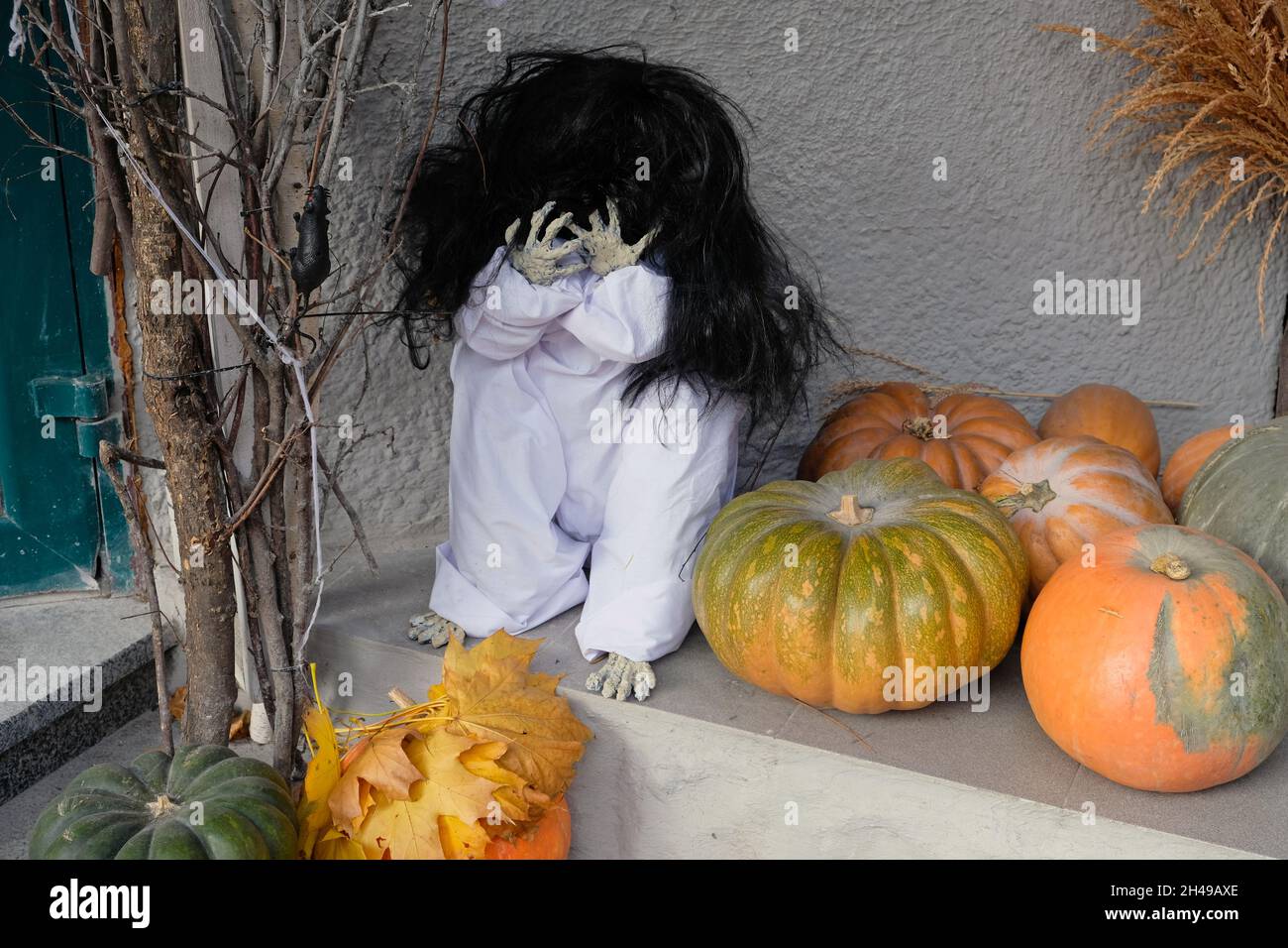 Decorazione della terrazza vicino al negozio di abbigliamento Halloween. Decorazioni divertenti per Halloween. Scary Doll che copre il suo viso e zucche per la vacanza. Foto Stock