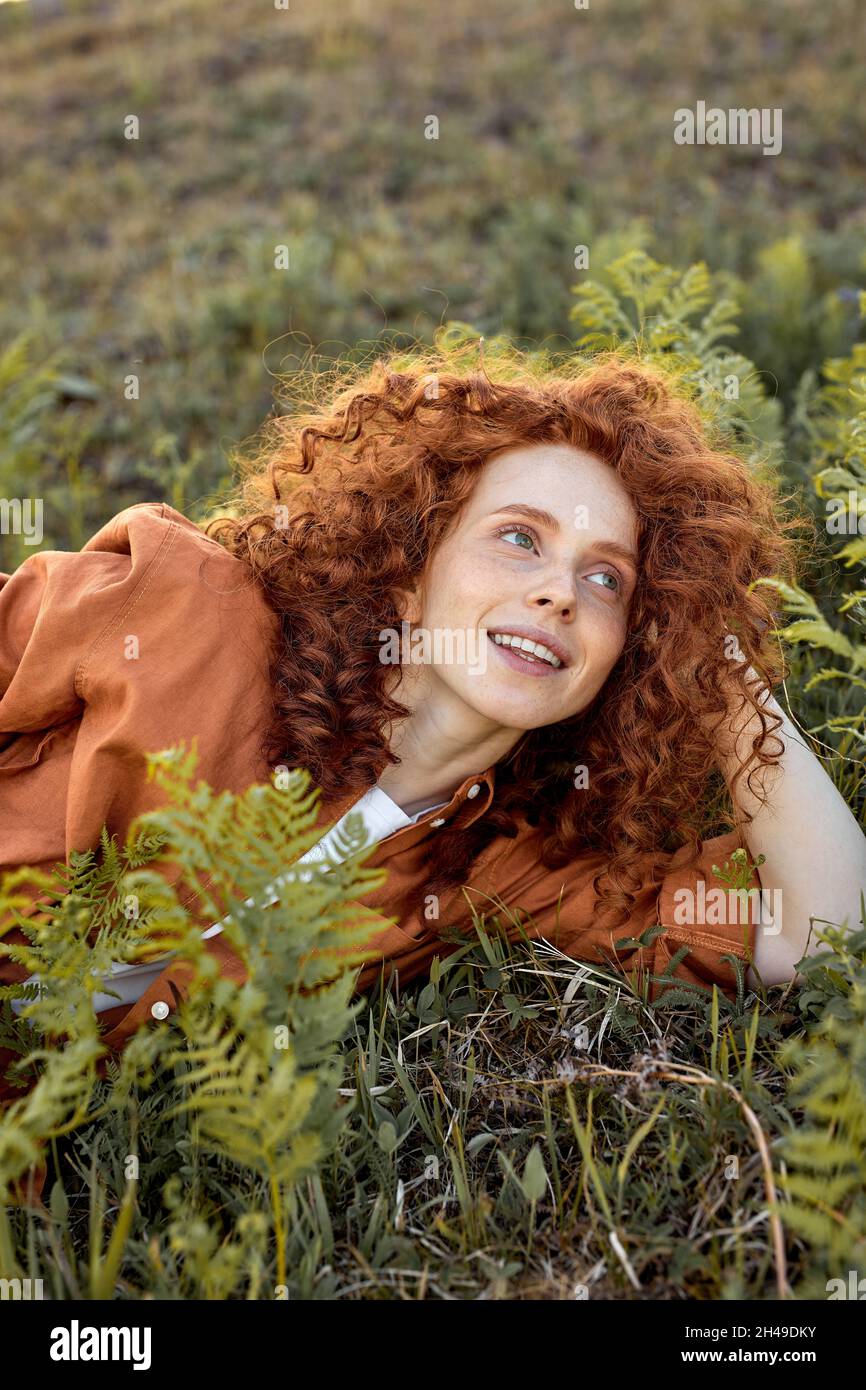 felice signora è sdraiata su erba verde in campo forestale, tempo romantico nella natura, relax. magnifica natura intorno, godere della vita. felicità, persone l Foto Stock