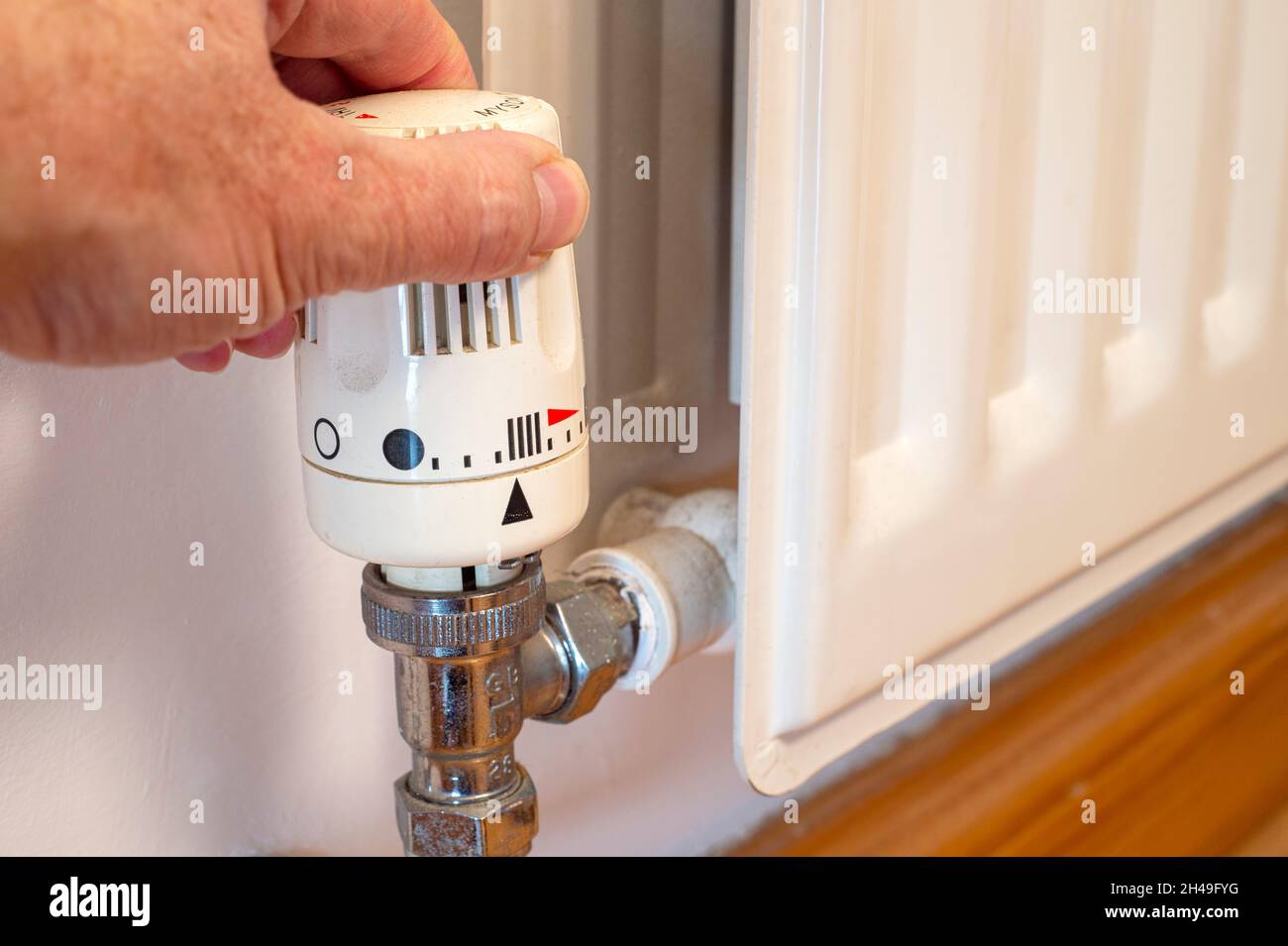 Mano dell'uomo che regola la temperatura di un radiatore Foto Stock