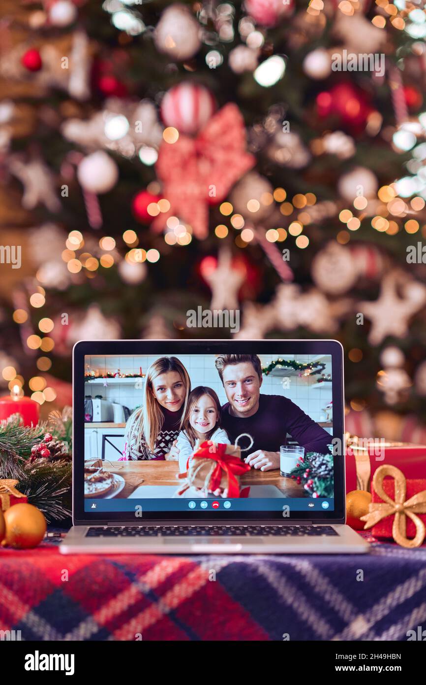 Videochiamata di famiglia sullo schermo del computer portatile sullo sfondo del tavolo di Natale. Foto Stock