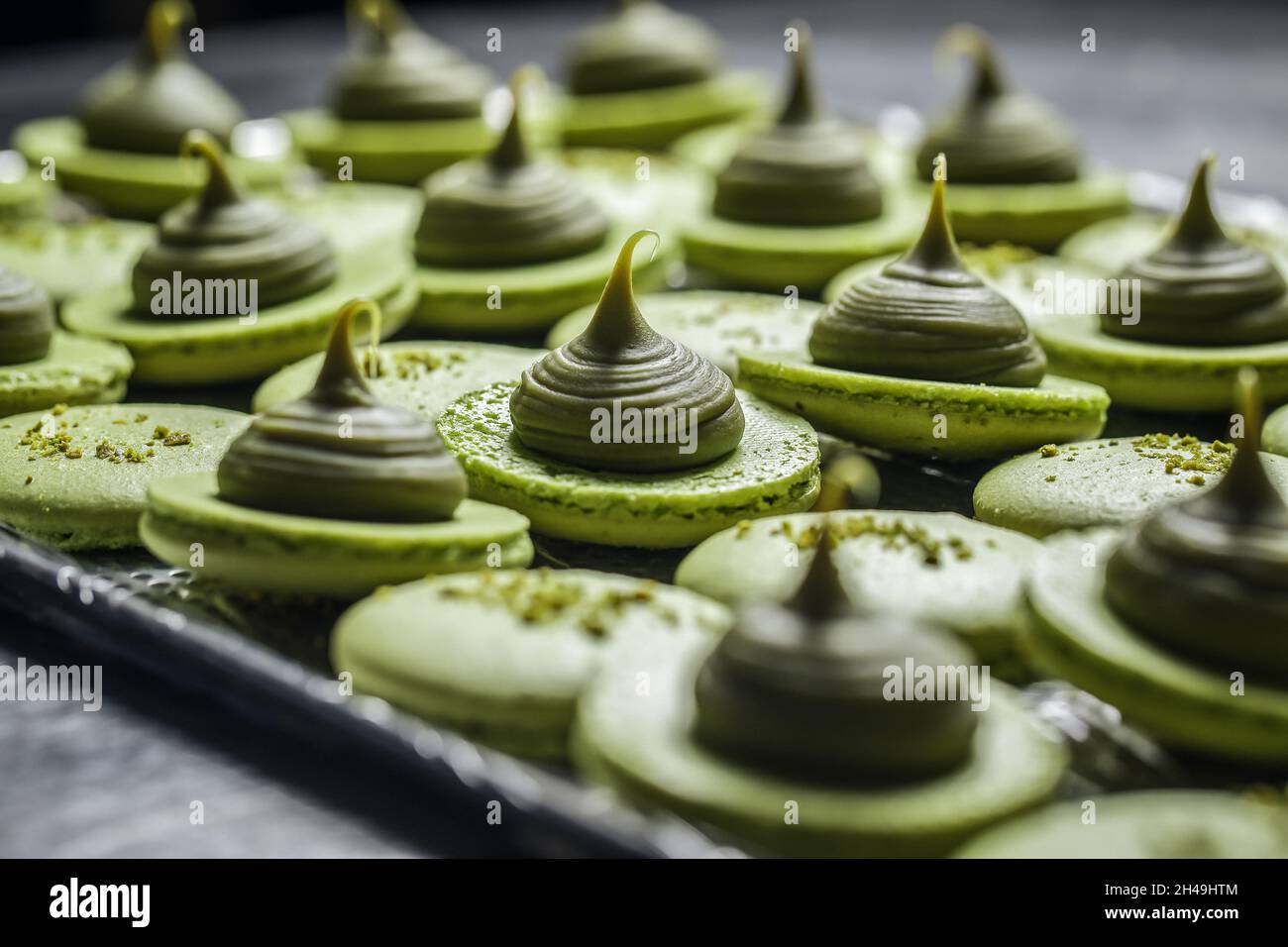 Processo di produzione di macaroni freschi fatti a mano in cucina ristorante. Biscotti colorati con macaroon su vassoi da forno Foto Stock