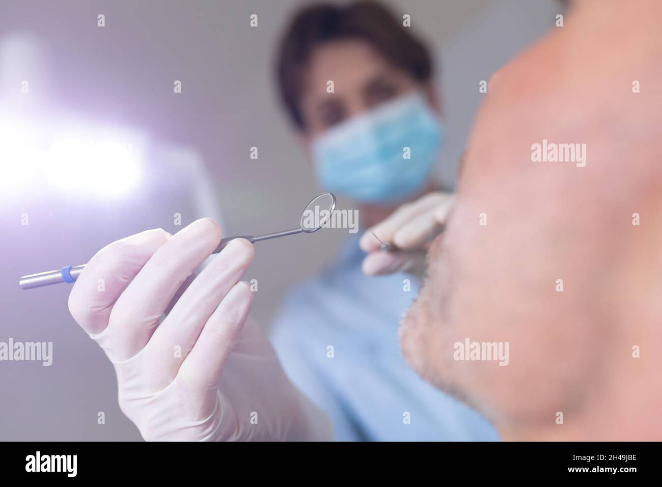 Infermiere dentale caucasico femmina che esamina i denti di un paziente maschio in clinica dentale moderna Foto Stock