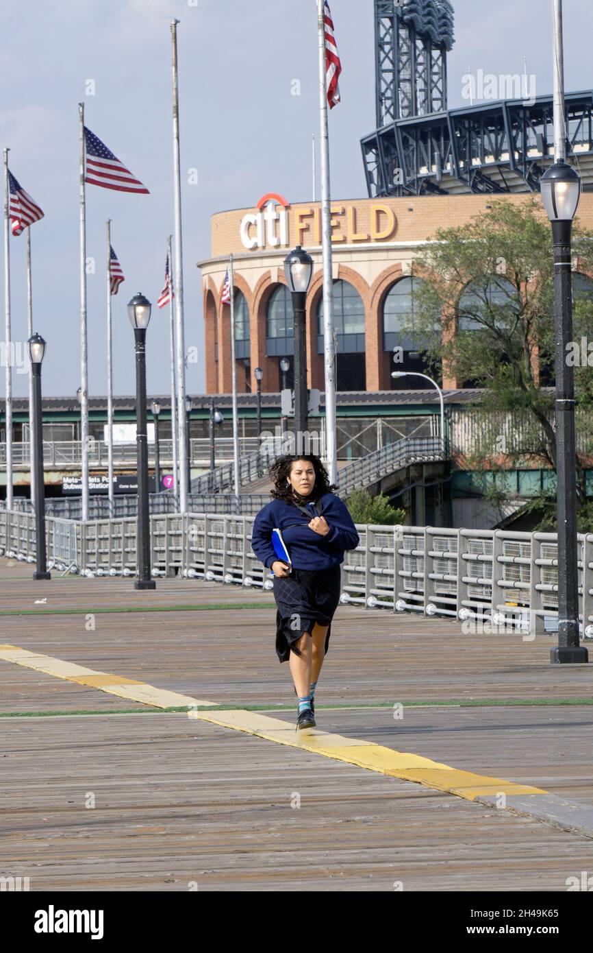 Una donna cammina bruscamente sulla rampa da Citi Field e la metropolitana verso Flushing Meadows Corona Park a Queens, New York City. Foto Stock