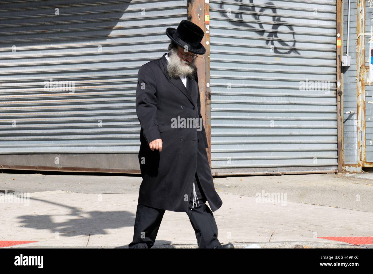 Un ebreo ortodosso cammina mentre si pensa profondamente. Su Lee Avenue a Williamsburg, Brooklyn, New York. Foto Stock
