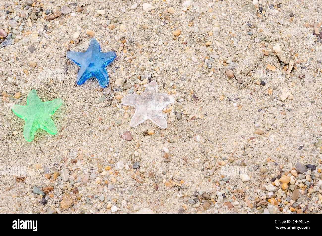 Tre stelle decorative su uno sfondo di sabbia da spiaggia con uno spazio copia, il concetto di una vacanza in un hotel a tre stelle Foto Stock
