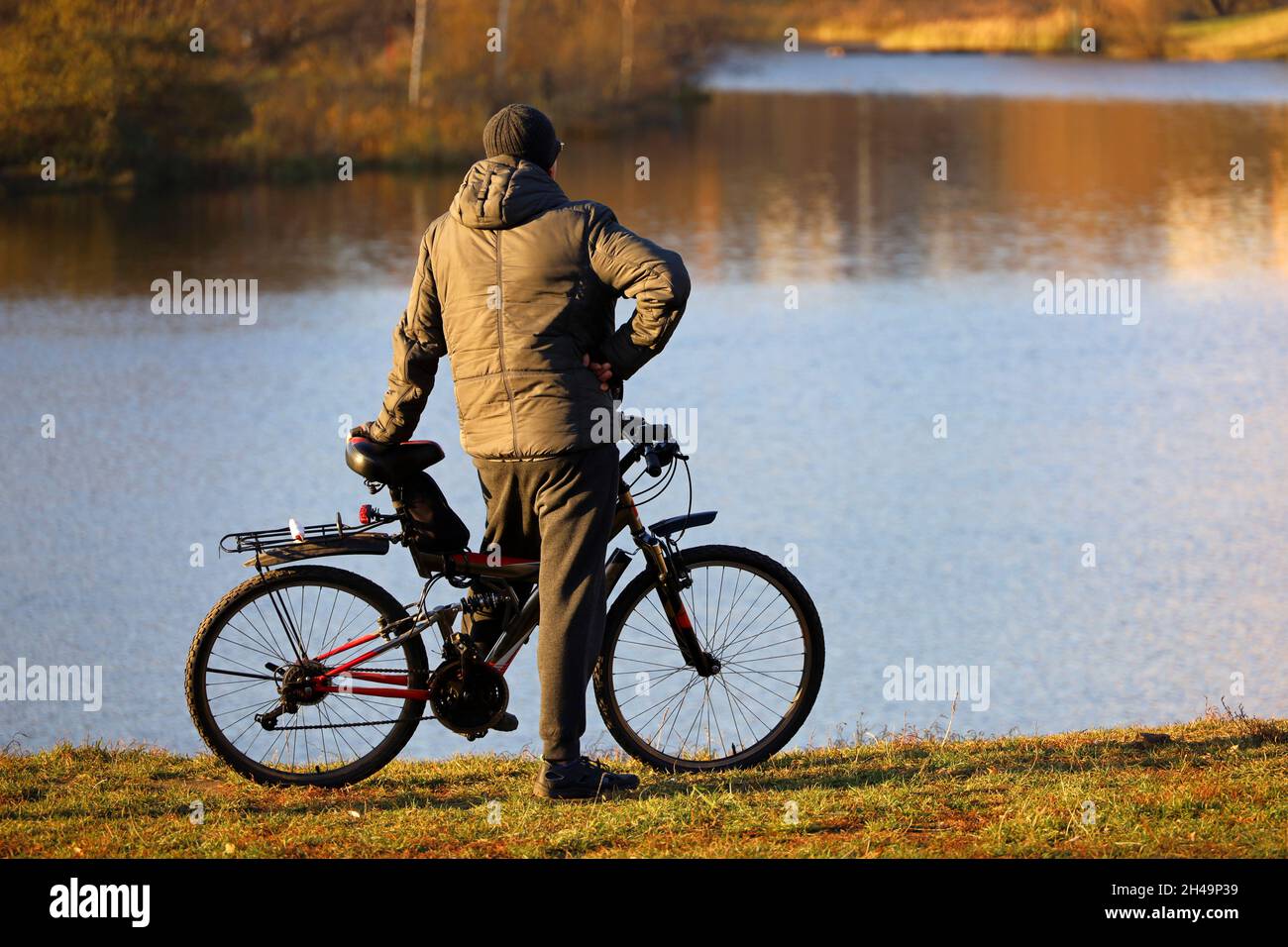 L'uomo si fermò in bicicletta sul lago e sullo sfondo della foresta autunnale. Ciclismo, viaggi e tempo libero in autunno stagione Foto Stock