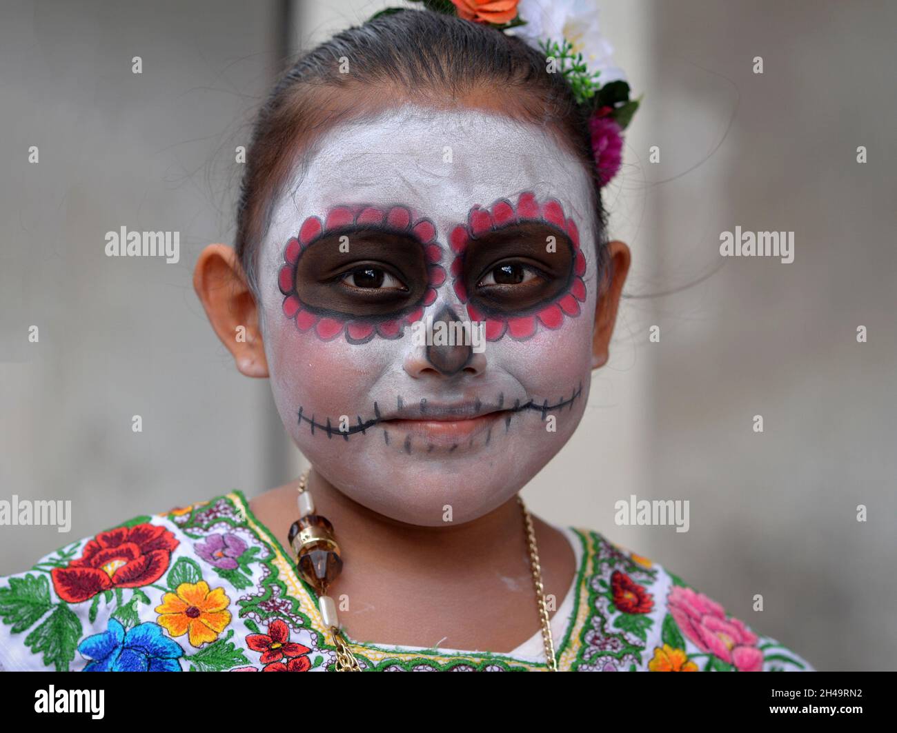 La bambina messicana dello Yucatecan con il trucco tradizionale del viso dipinto (calavera) il giorno dei morti (dia de los Muertos) guarda lo spettatore. Foto Stock