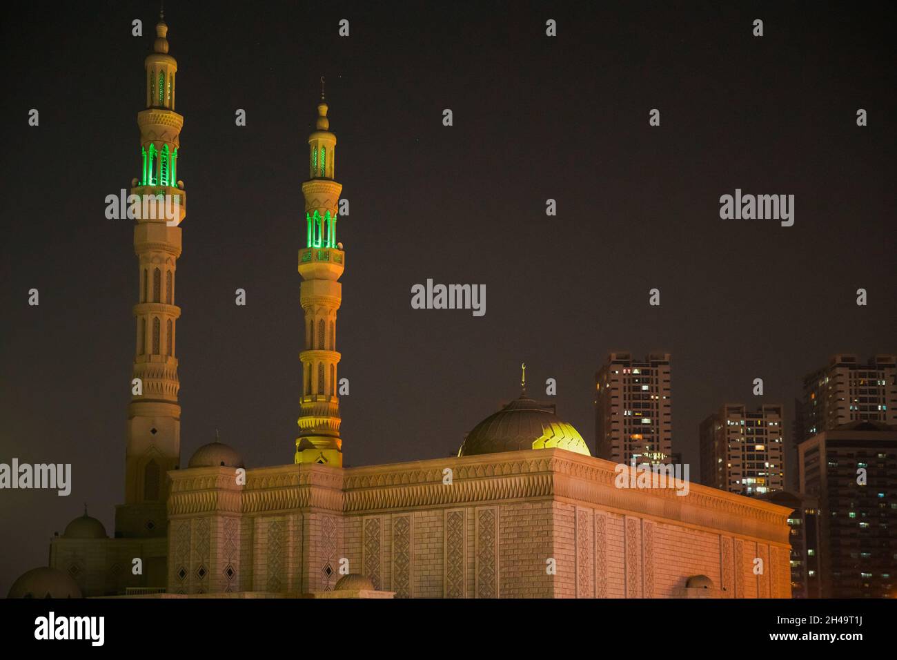 Vista notturna della moschea di al Remeila, nuove case residenziali a più piani ad Ajman, Emirati Arabi Uniti Foto Stock