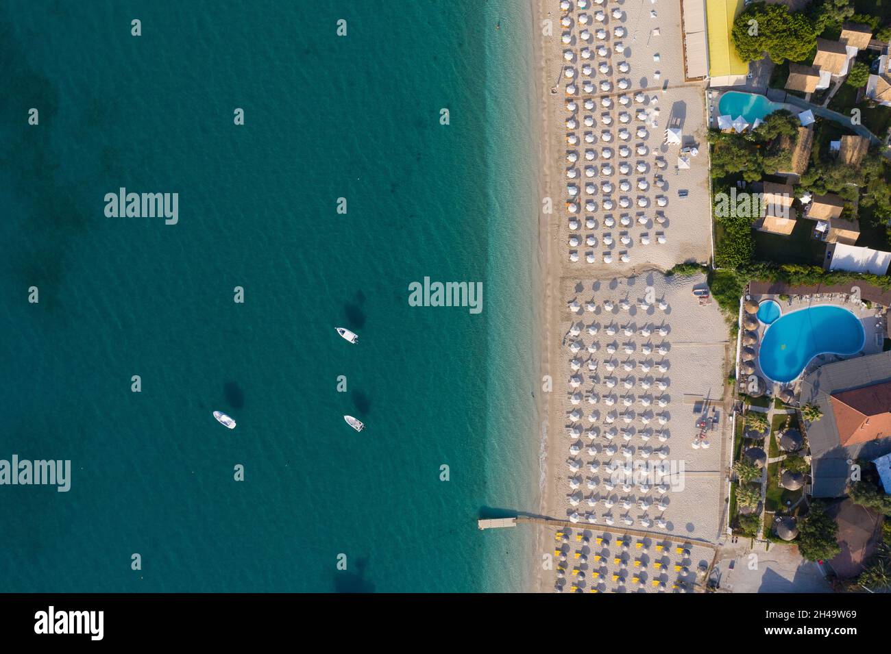 Scatto aereo di barche a vela ormeggiate e ombrelloni presso la spiaggia organizzata di Valtos a Parga Grecia Foto Stock