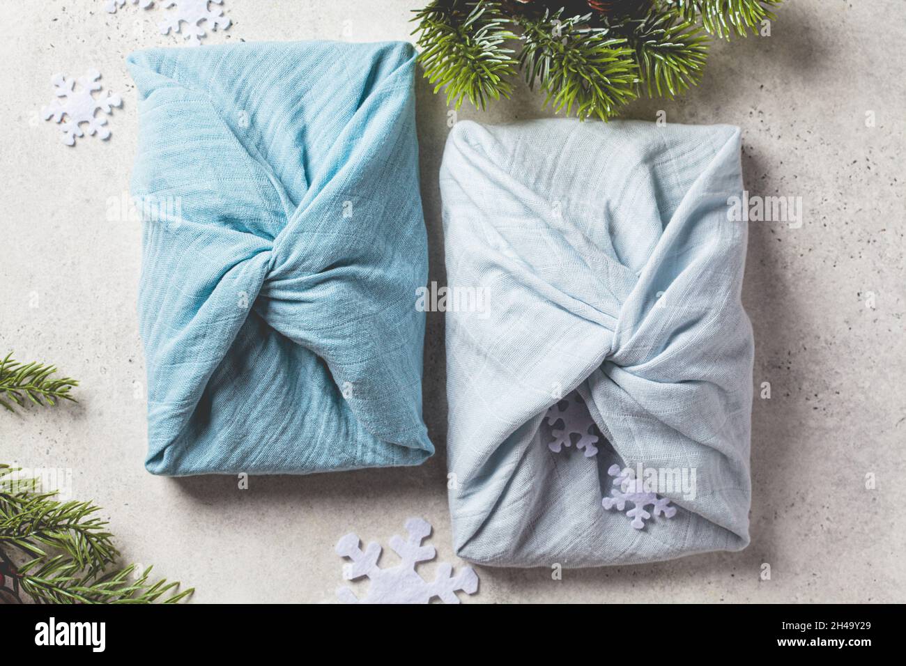 Articoli regalo in tessuto per Natale su sfondo grigio, vista dall'alto. Concetto di zero rifiuti. Stile Furoshiki. Foto Stock