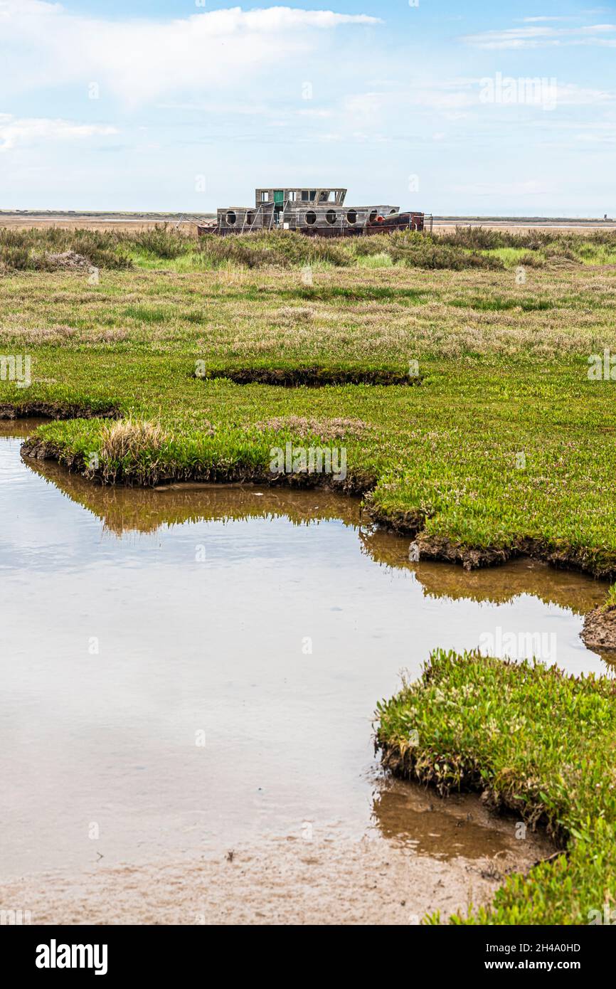 Una vecchia barca derelitto accanto al fiume Glaven sulle paludi saline alla Riserva Naturale Nazionale di Blakeney a Blakeney, Norfolk UK Foto Stock
