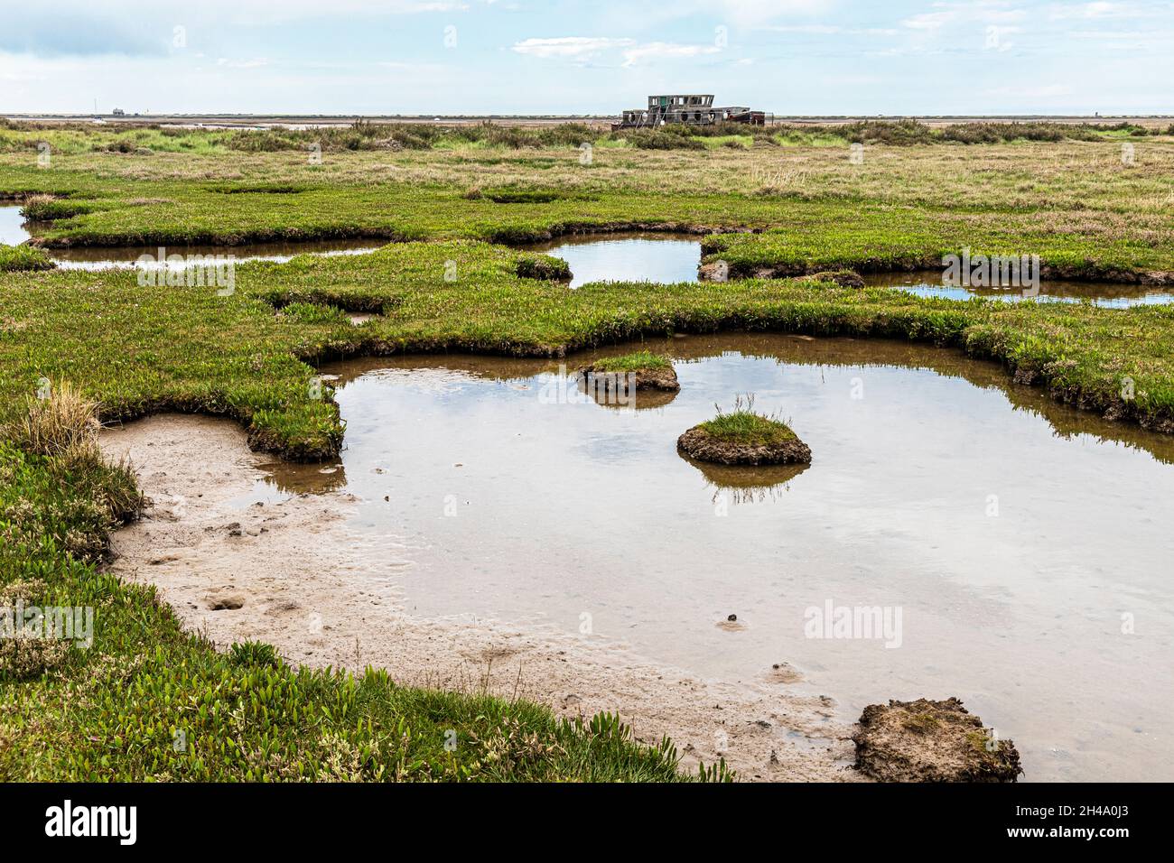 Una vecchia barca derelitto accanto al fiume Glaven sulle paludi saline alla Riserva Naturale Nazionale di Blakeney a Blakeney, Norfolk UK Foto Stock