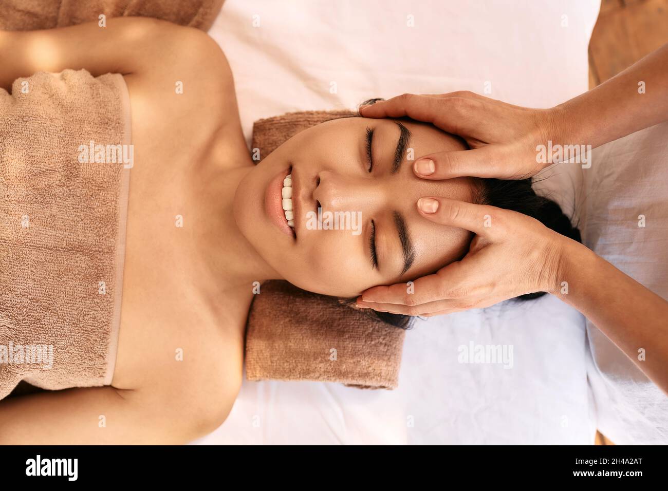 La donna asiatica riceve un massaggio alla testa e gode di relax presso la spa. Massaggio anti-stress alla testa Foto Stock